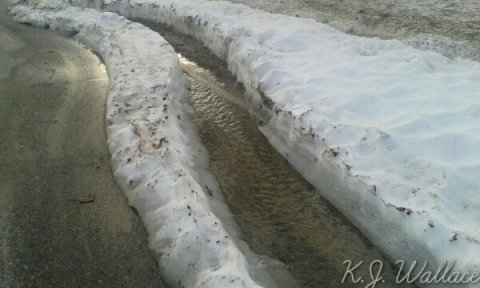Running water in between two mounds of melting snow
